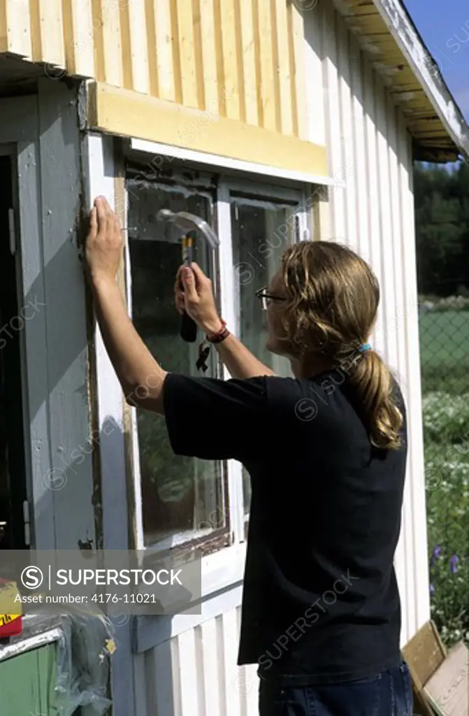 Young man with hammer renovating a house in Sweden