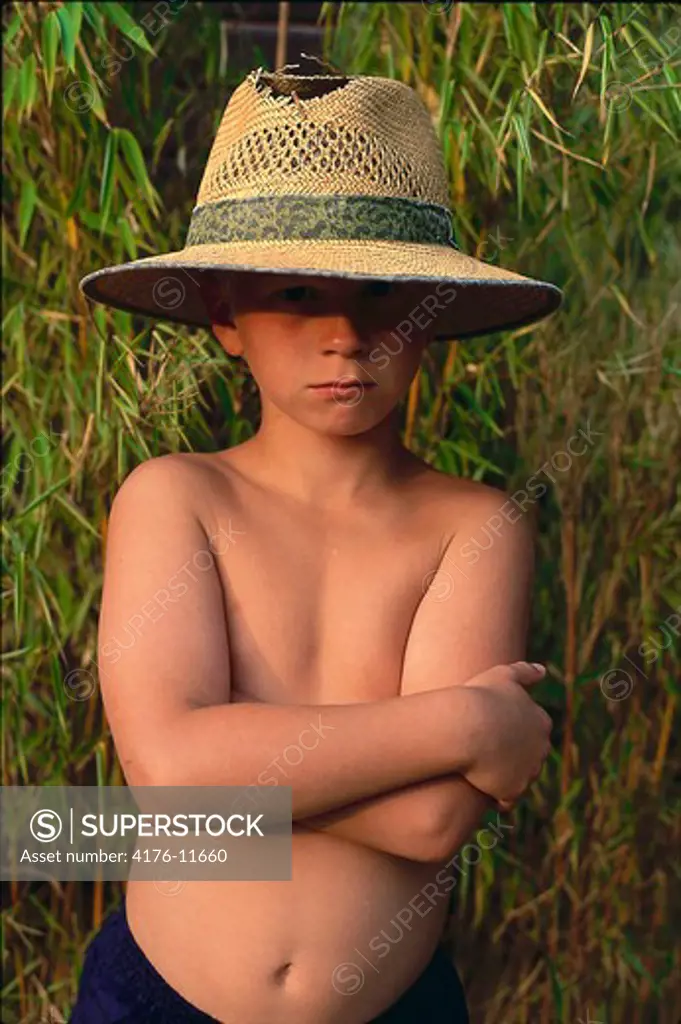 A boy wearing torn hat and looking at the camera