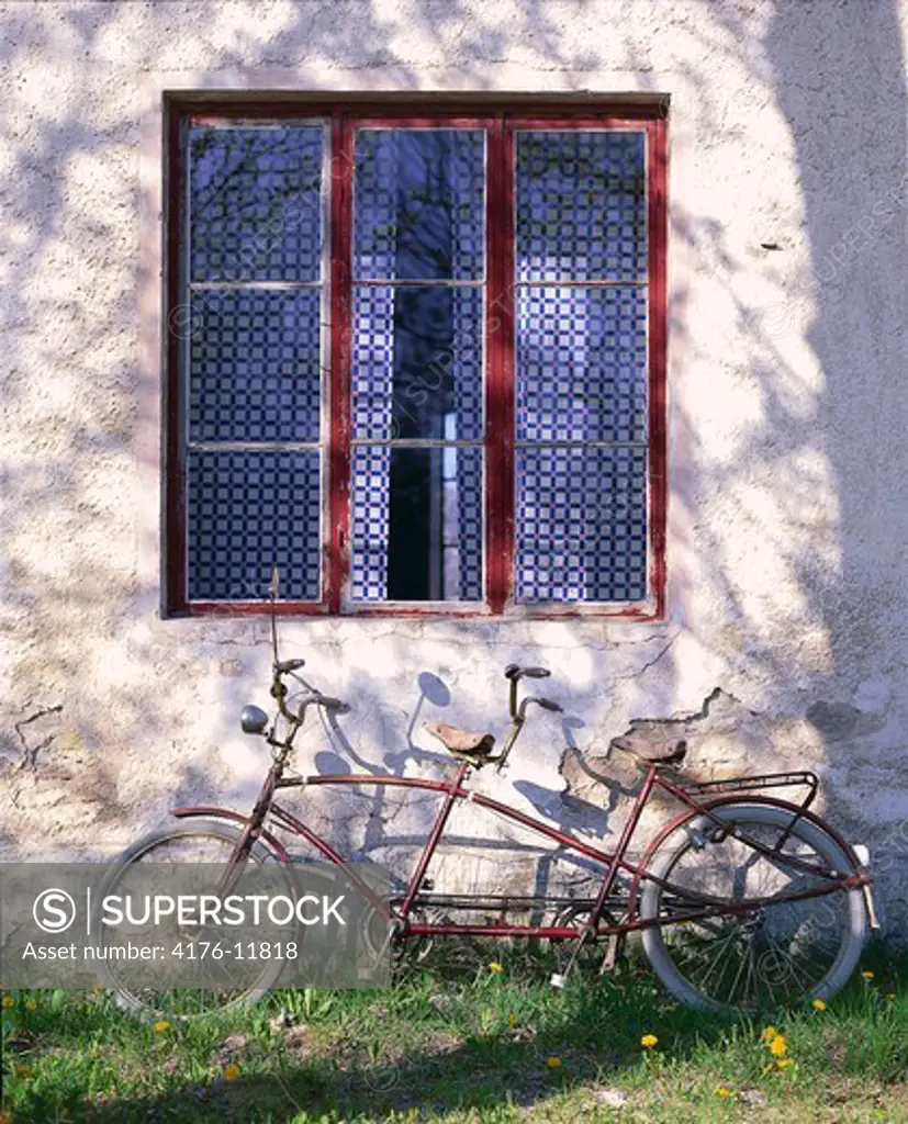 A tandem bicycle standing near the wall