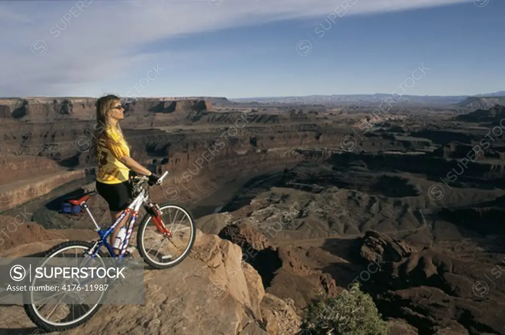 A lady standing with her bicycle on the edge of the mountain in Utah, USA