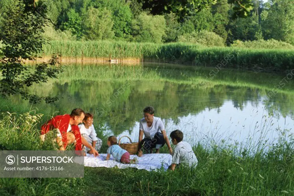 Family picnic near countryside pond
