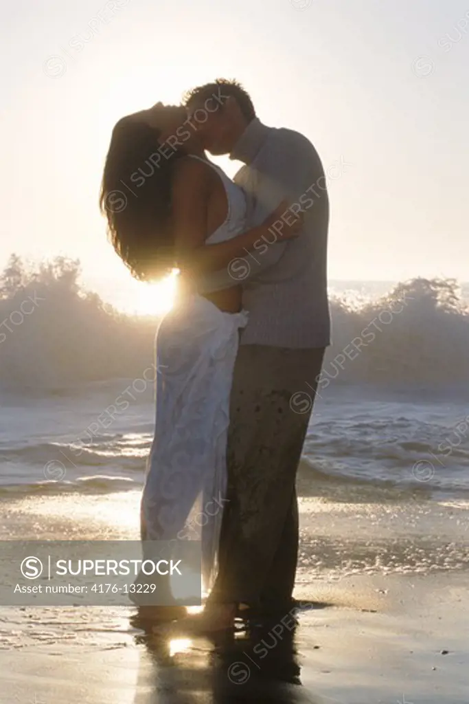 Couple on California beach embracing at sunset