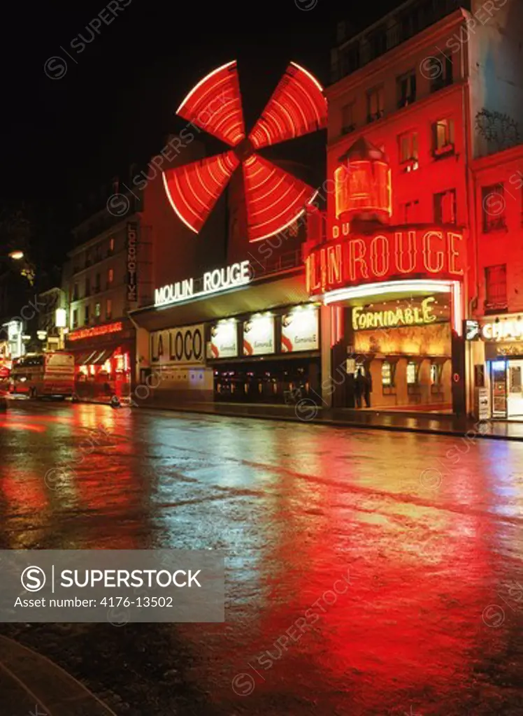 Moulin Rouge reflecting off wet street in Pigalle district of Paris at night