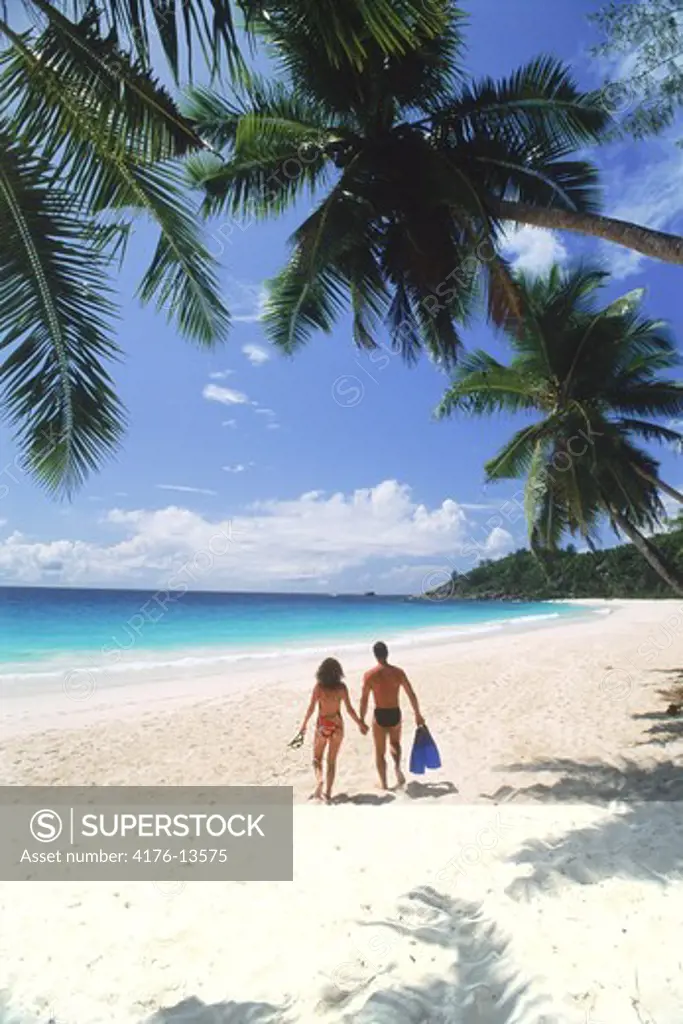 Couple with swim fins running across Intendence Beach on Mahe Island in Seychelles