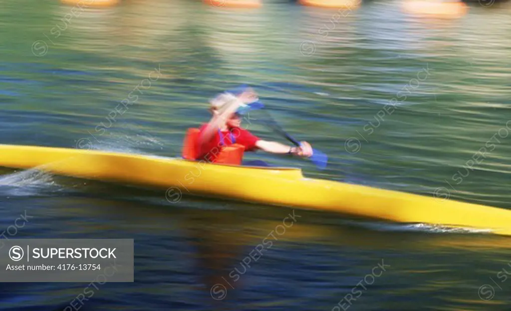 Young Scandinavian paddling yellow kayak on Stockholm city canal