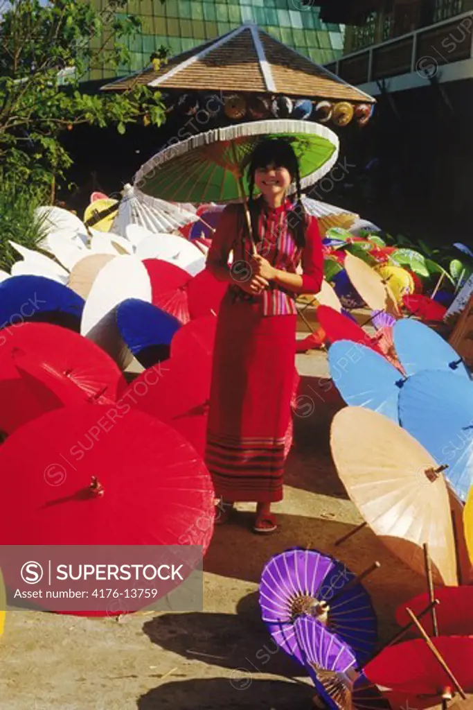 Thai woman surrounded by painted umbrellas in Chiang Mai Thailand