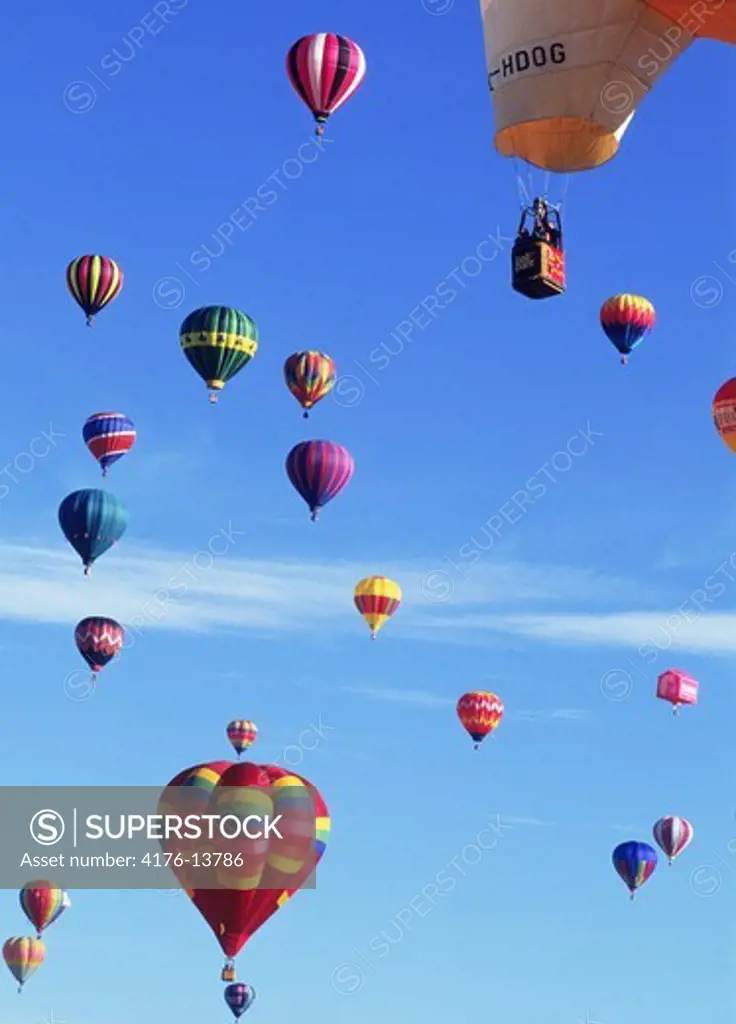 Floating balls of colorful silk carrying baskets of people through clear blue skies