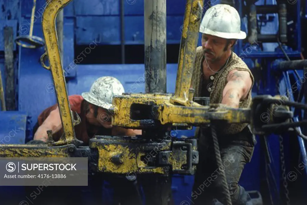 Men working on offshore oil rig coupling drill bits.