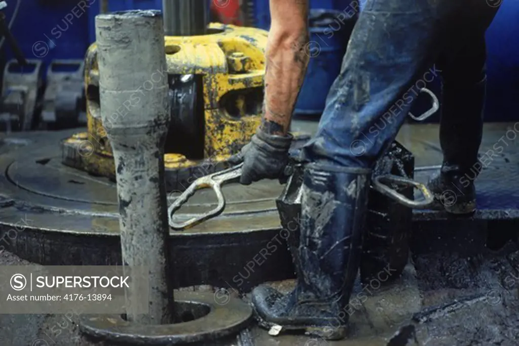 Hands holding drilling bit on offshore oil derrick