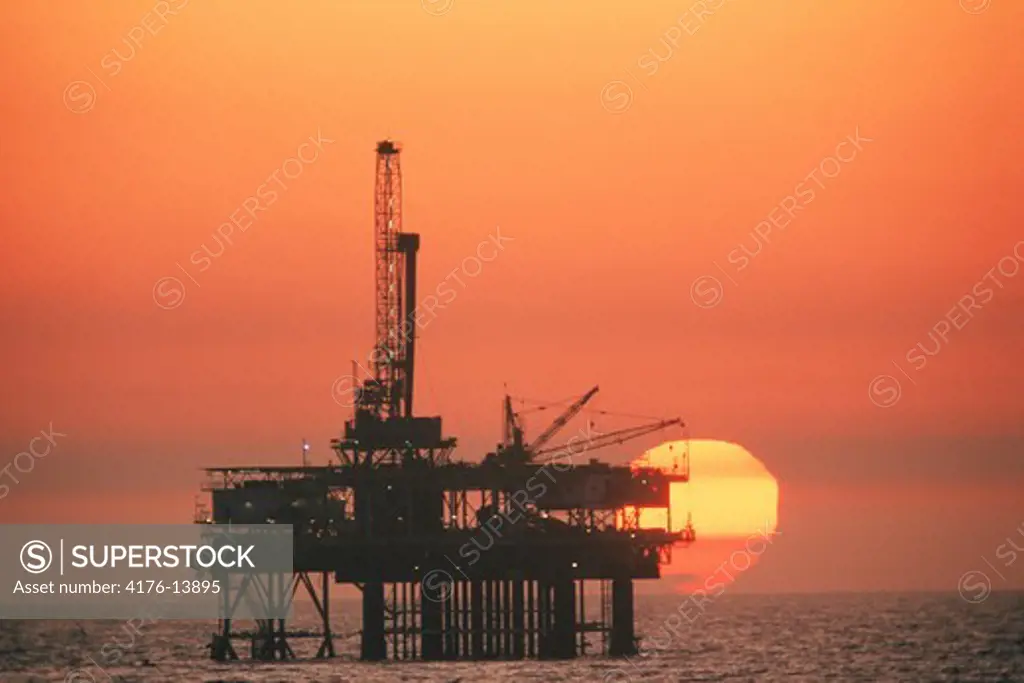 Offshore oil rig silhouetted by sunset at Huntington Beach California