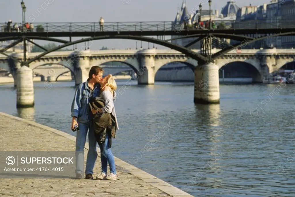 Couple walking along River Seine near Pont des Arts in Paris
