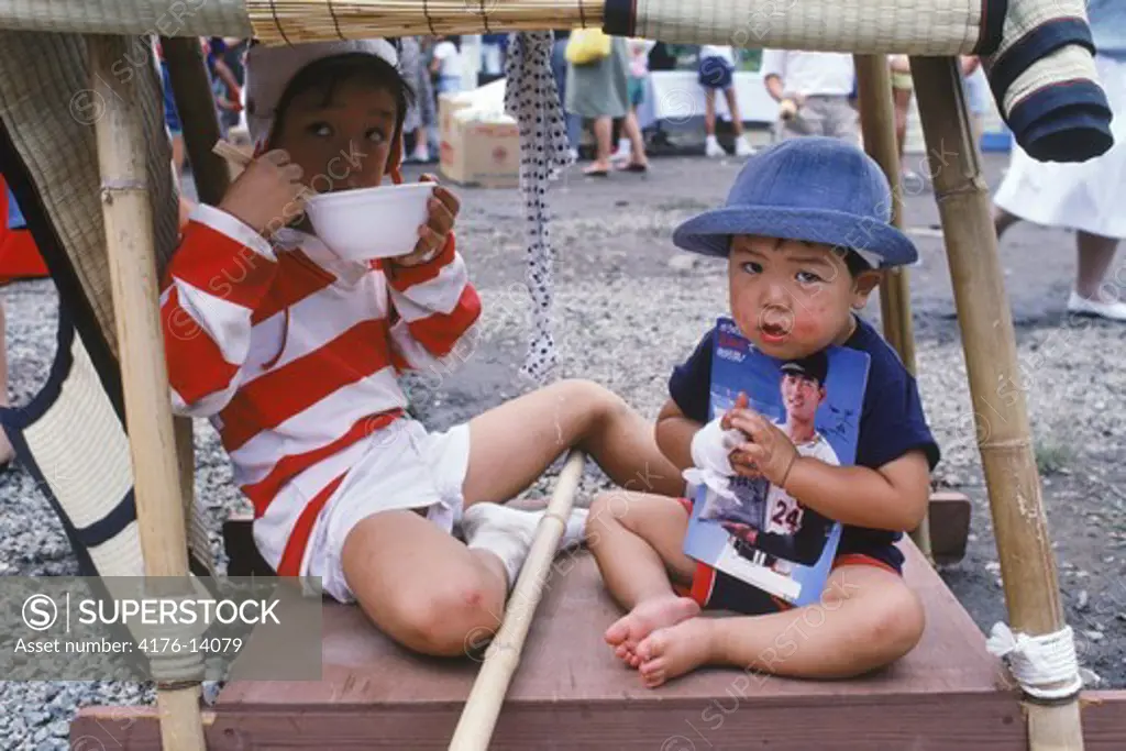 Japanese children eating snacks and holding souviner baseball program
