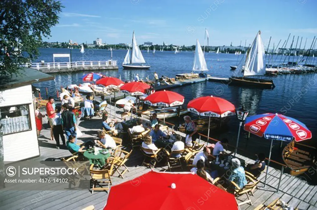 Pier cafe and tables with sailboats on Alster Lake in the middle of Hamburg in Northern Germany