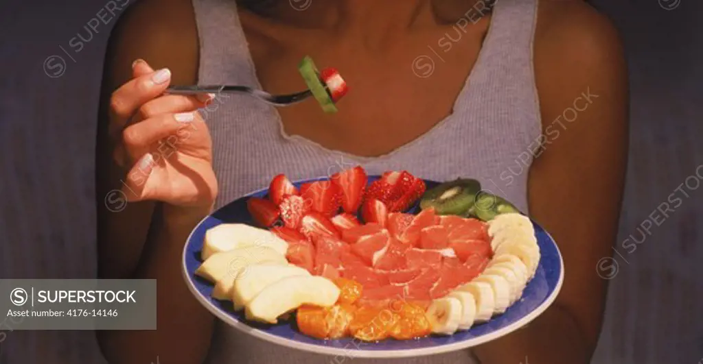 Woman eating variety of fruits for breakfast