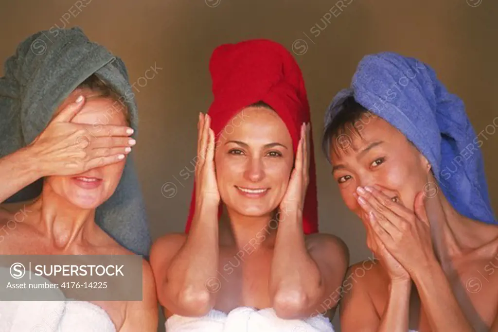 Three women of ethnic mix with colorful bath towels expressing old Asian proverb, ""See no evil, hear no evil, speak no evil""