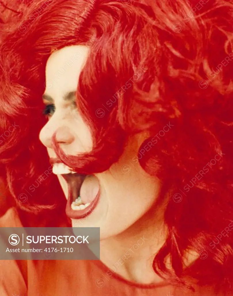 Close-up of a young woman with red hair screaming