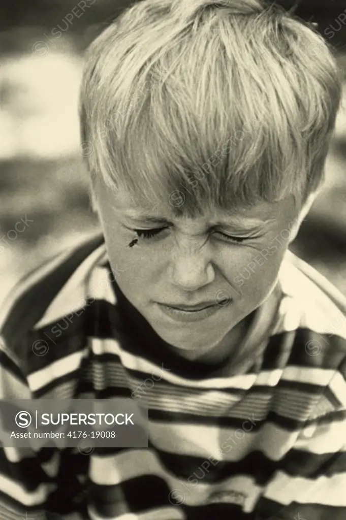 A boy closing his eyes with being irritated by a housefly