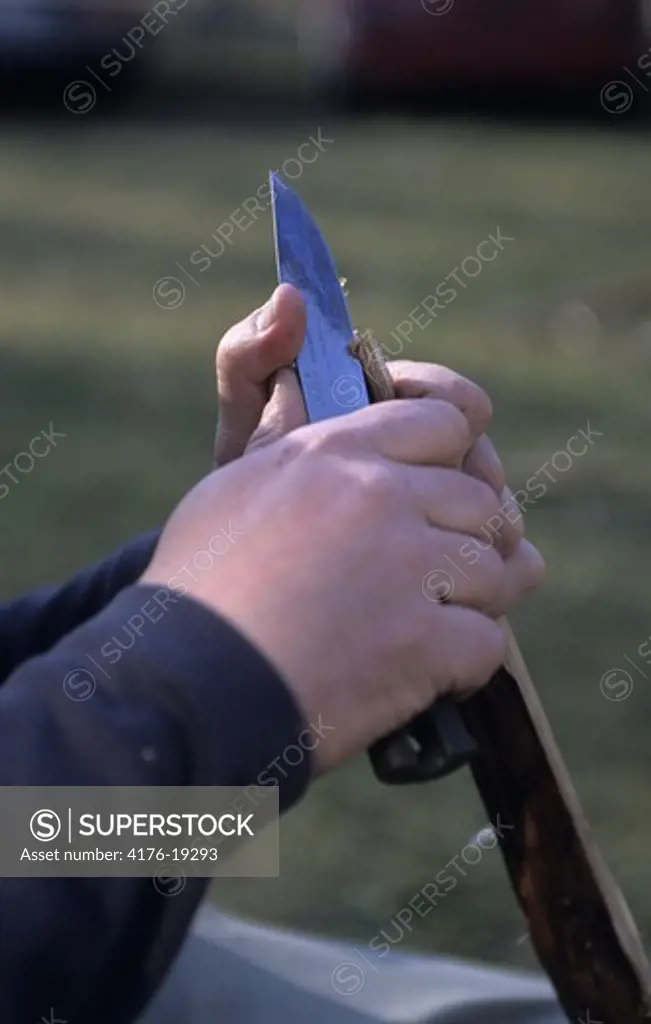 A person cutting wood with a knife