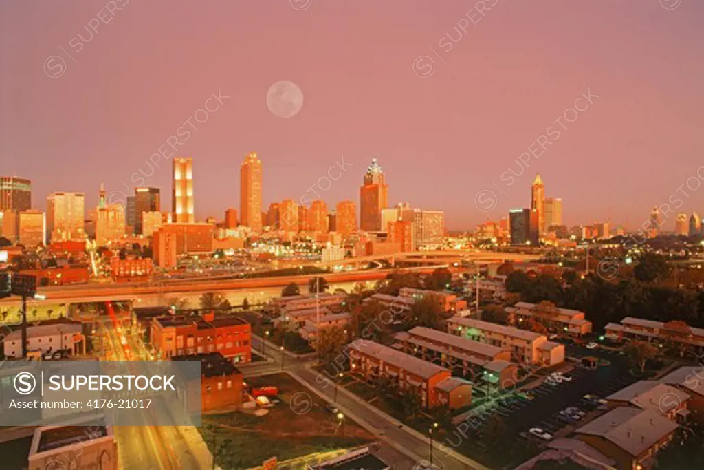 City skyline, apartment buildings and roads around Atlanta under full moon at dusk