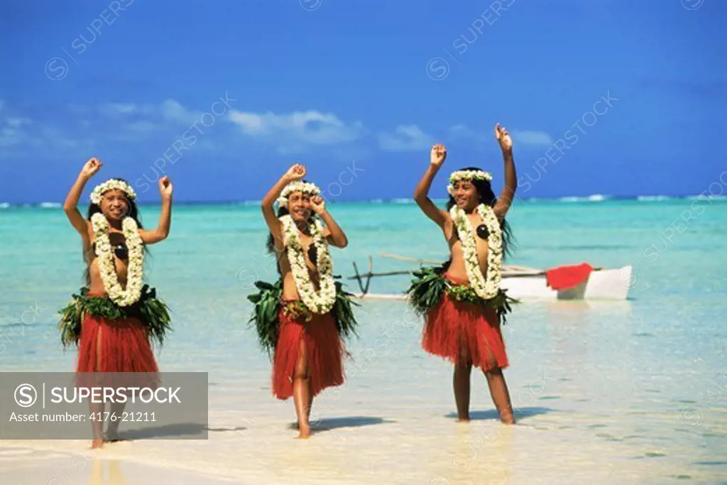 Three Polynesian girls with outrigger in Aitutaki lagoon