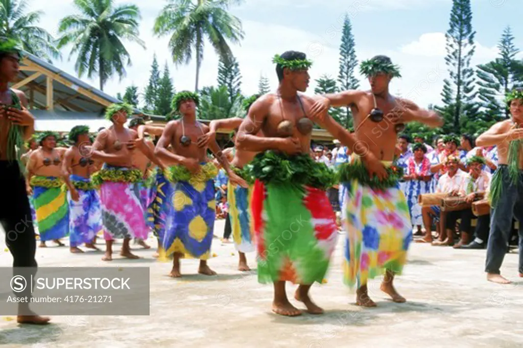 Polynesian men in women's dress dancing playfully to native music on Aitutaki in Cook Islands  South Pacific