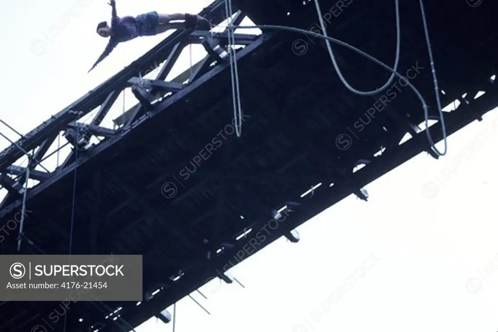 Low angle view of a woman bungee jumping from a bridge