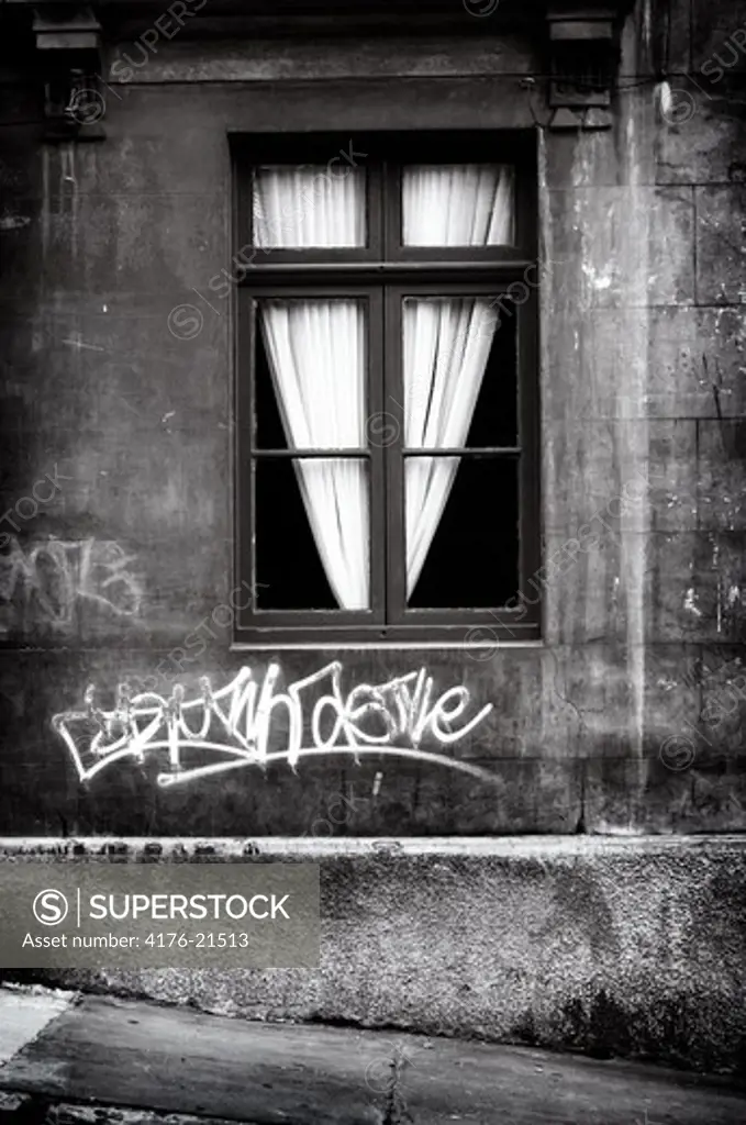 Graffiti under a window on a wall
