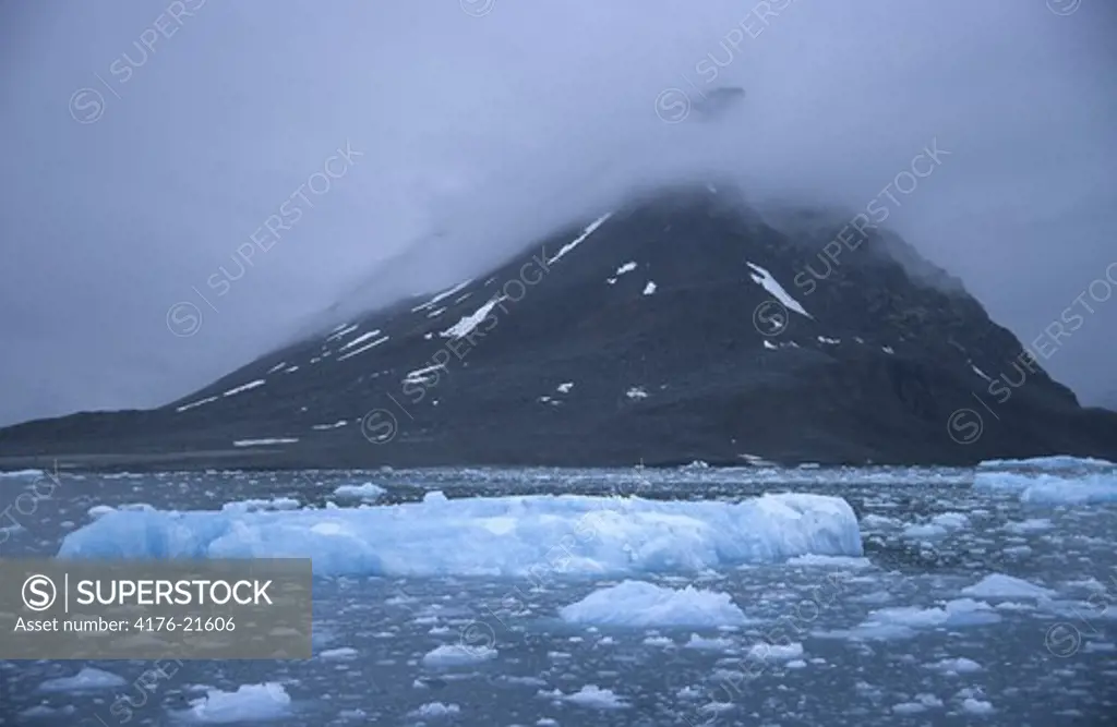 Ice floes in water and mountain in the background