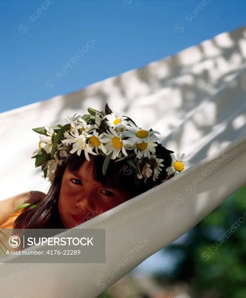 Portrait of a girl wearing flowers and lying in a hammock