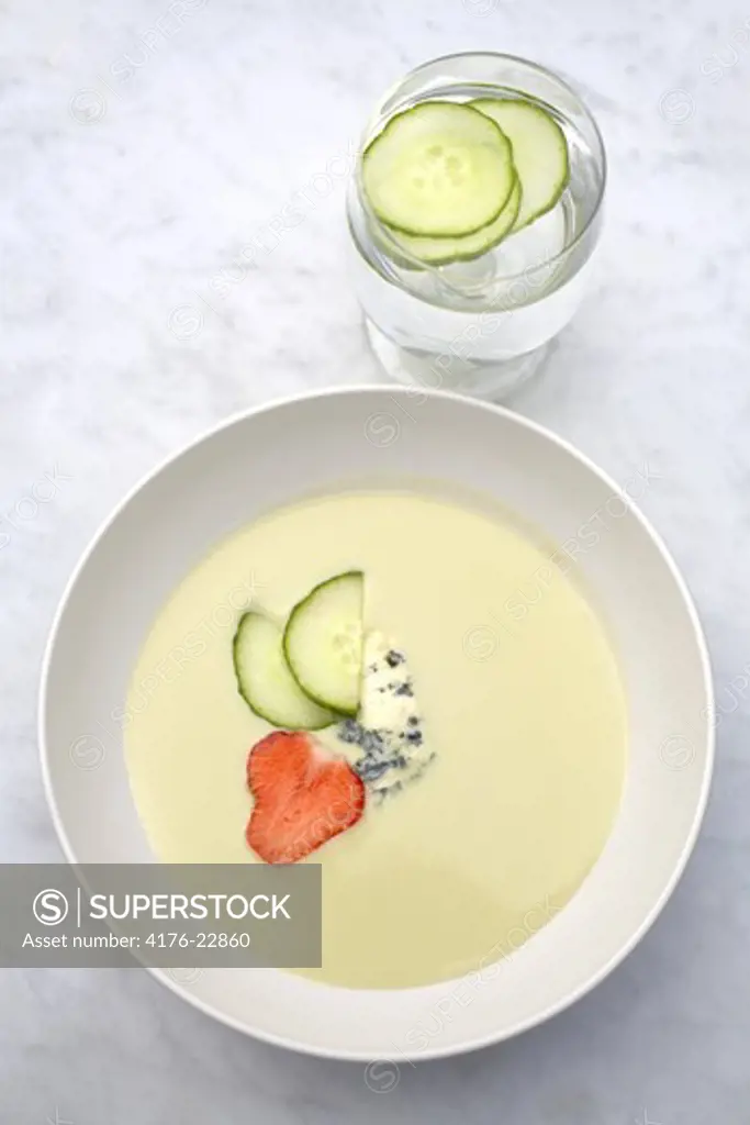 Cucumber soup in a bowl with slices of cucumbers in a glass of water