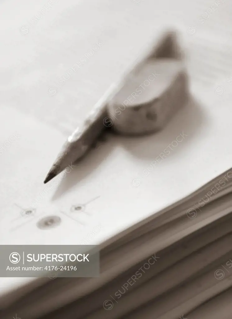 Close-up of a pencil and an eraser on a stack of papers
