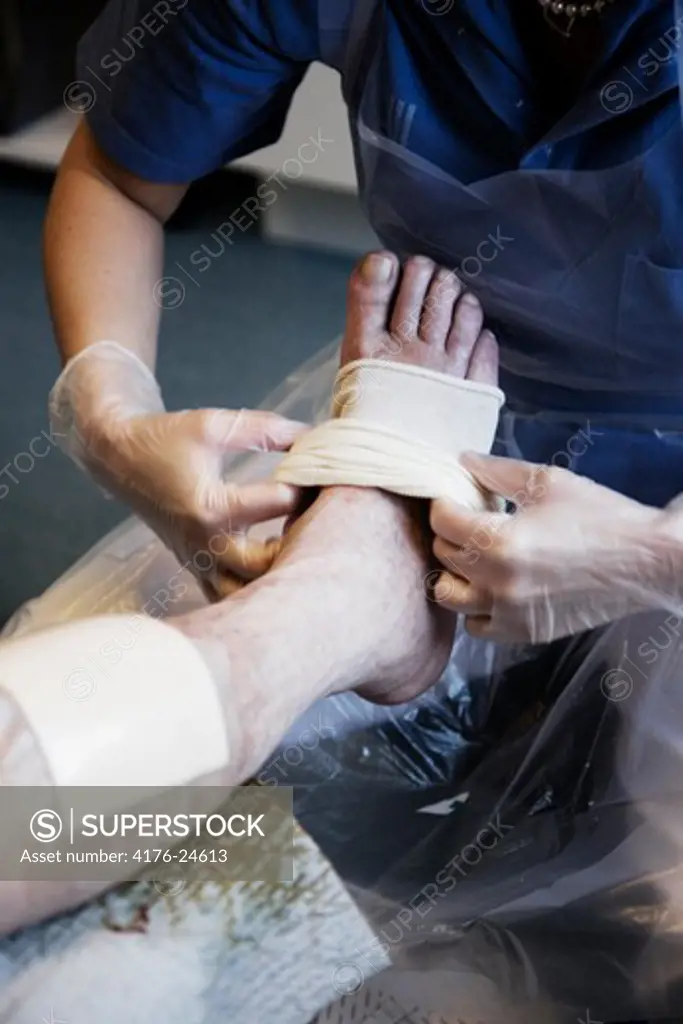 Mid section view of a doctor dressing a patient's leg