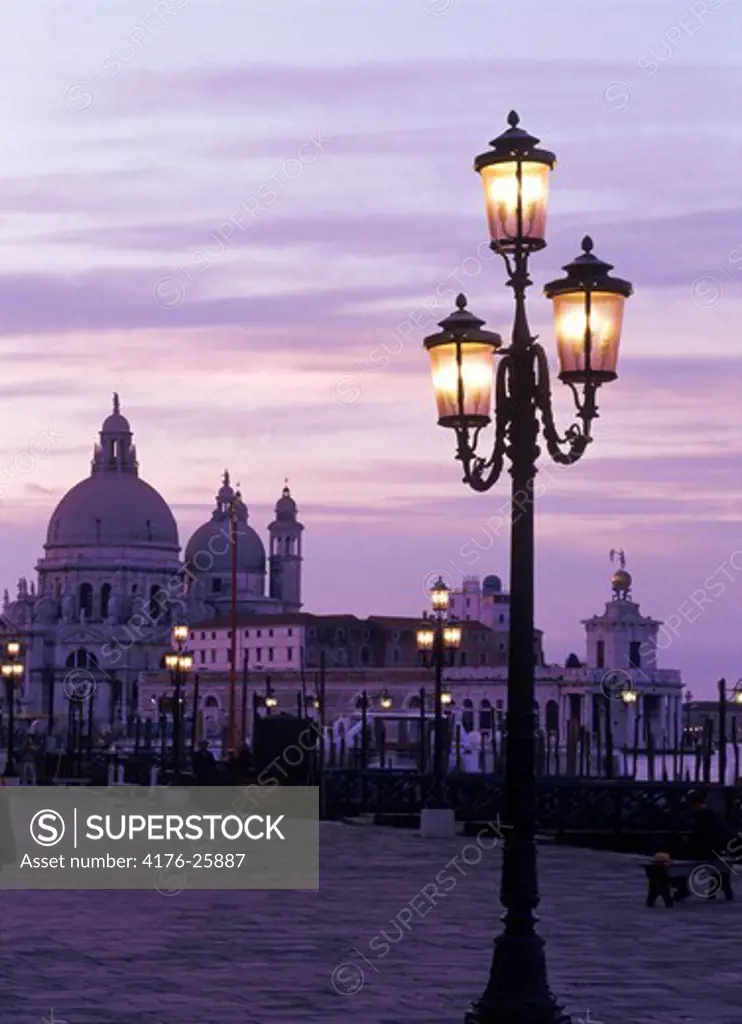 Lamps along St Marks Basin with Santa Maria della Salute church at dusk in Venice