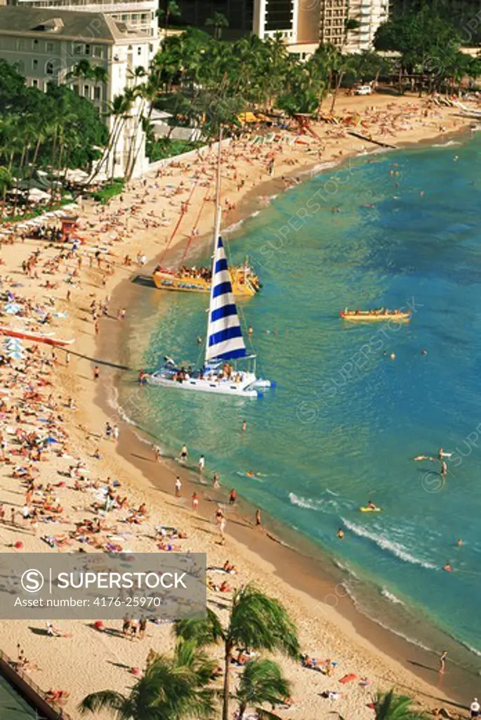 Waikiki Beach in Honolulu with catamarans, outrigger canoe and sunbathers