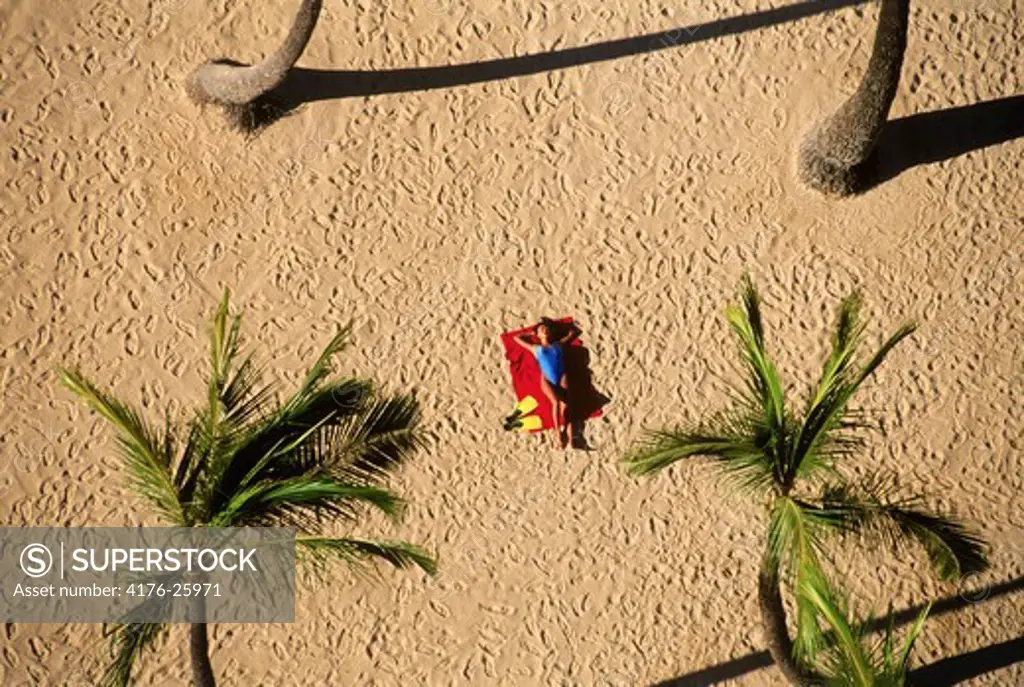 Woman alone on Waikiki Beach amid palm trees from above