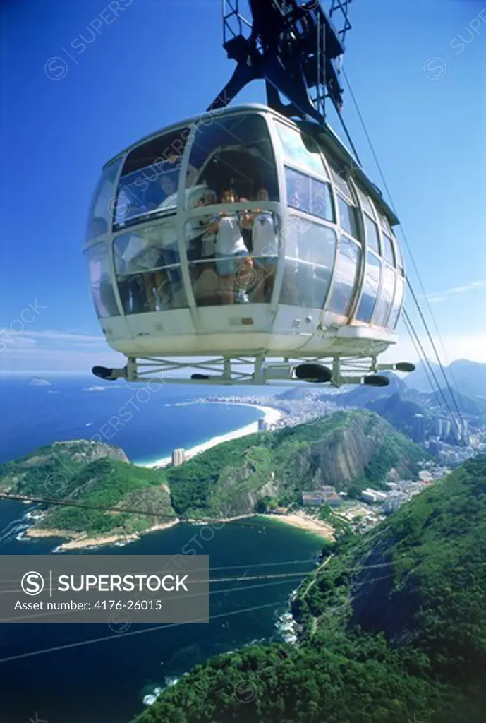 Cable car loaded with passengers nearing top of Sugar Loaf with Rio below