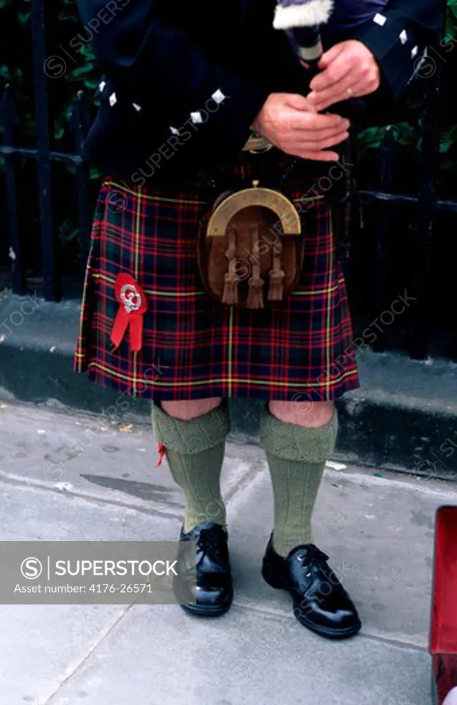 Low section view of a man in a kilt playing a bagpipe