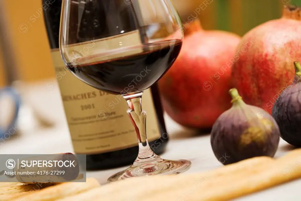 Close-up of a glass of red wine and wine bottle with fruits on a table
