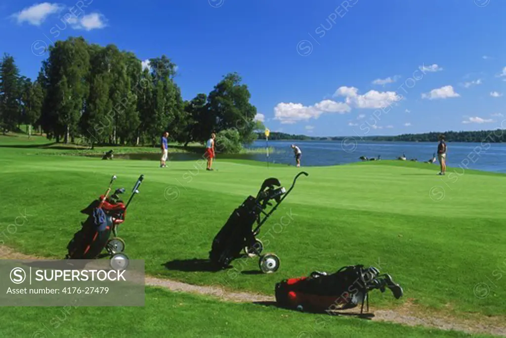 Golf carts and players on Taby Golf Course green near Stockholm in Sweden