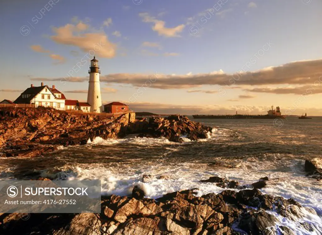 Ship passing Portland Head Lighthouse on coast of Maine at sunrise