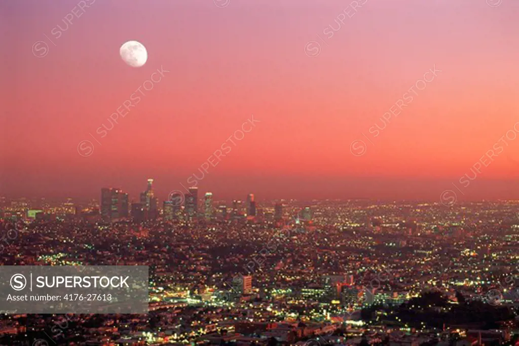 Los Angeles Civic Center amid urban sprawl under rising moon at dusk from Griffith Park Observatory