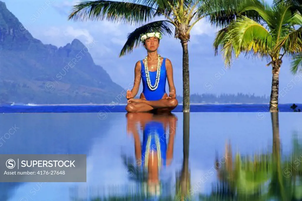 Woman in yoga position on poolside at Hanalei Bay on Kauai Island in Hawaii