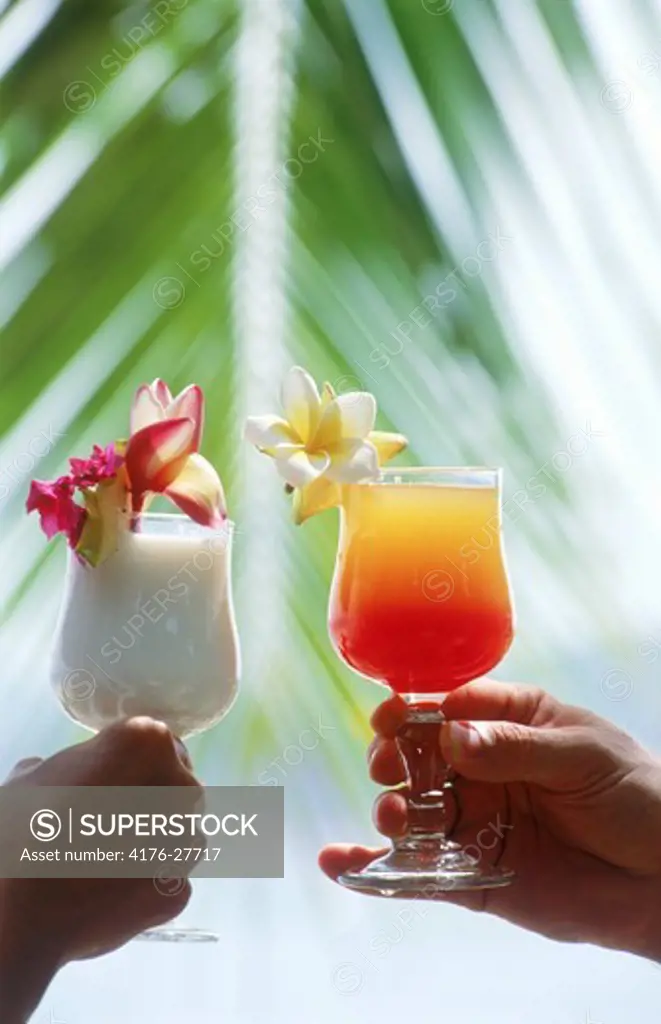 Couple on island holiday toasting with tropical drinks