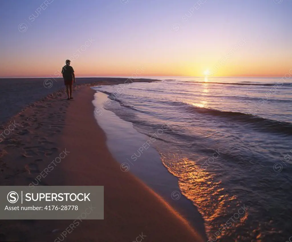 Person walking at beach in sunset, Sweden