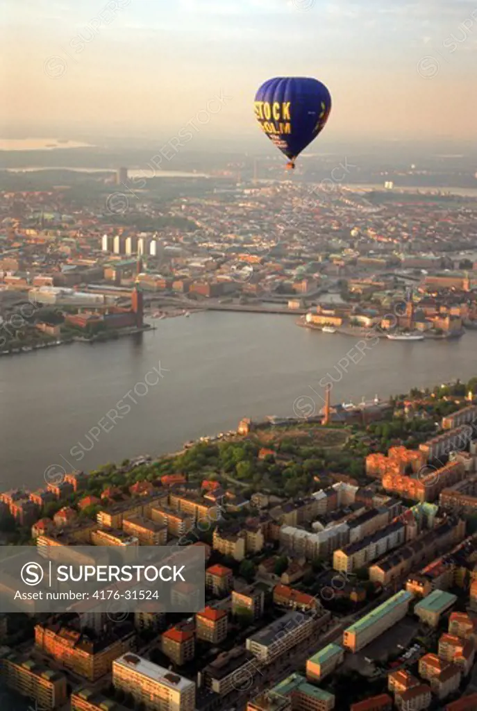 Hot air balloon floating over islands of Stockholm and Riddarfjarden waters at sunset with City Hall