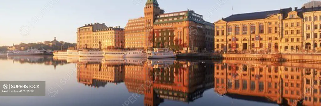 SAS Radisson Hotel and waterfront buildings with moored ships at Nybroviken in Stockholm at sunrise