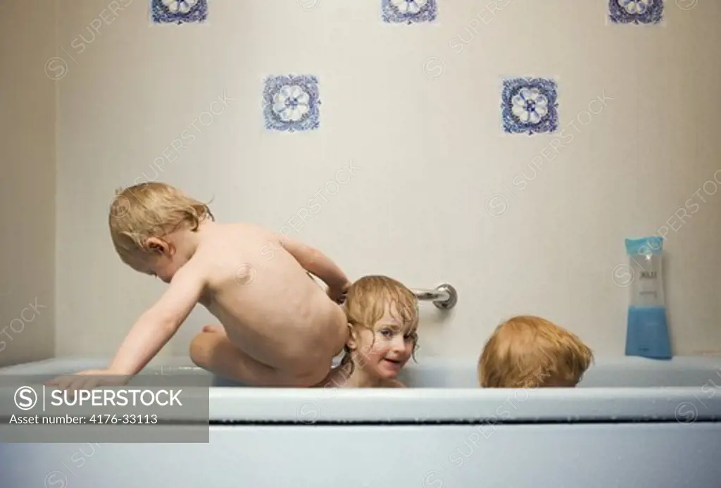 Three children in a bathtub doing trix, Sweden.