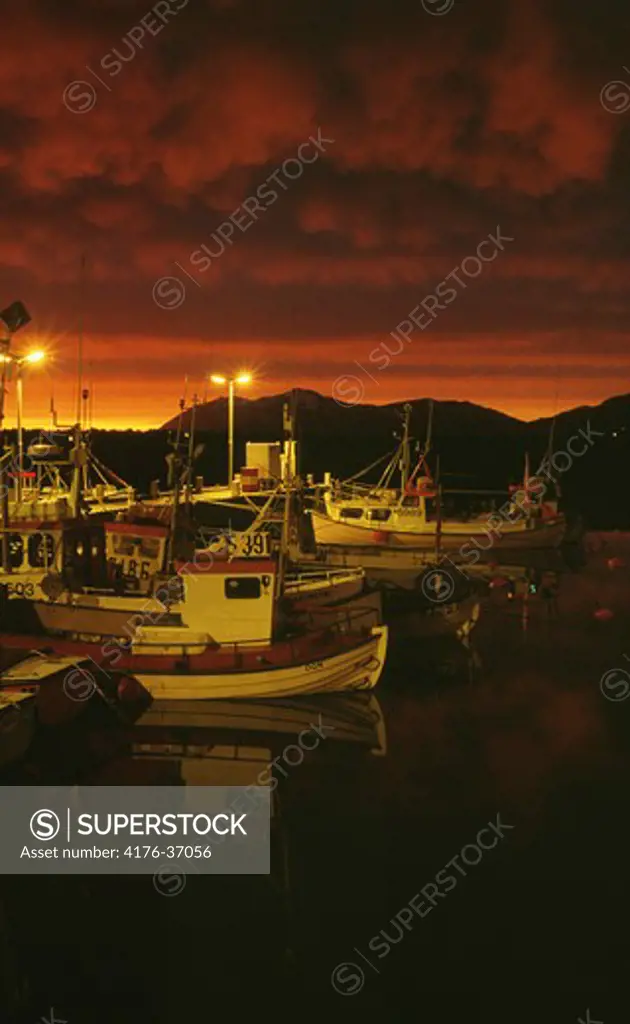 Boats in a small harbour beneath a magnificently colorful sky
