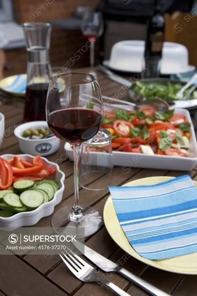 Wine glass next to tomato salad on a table