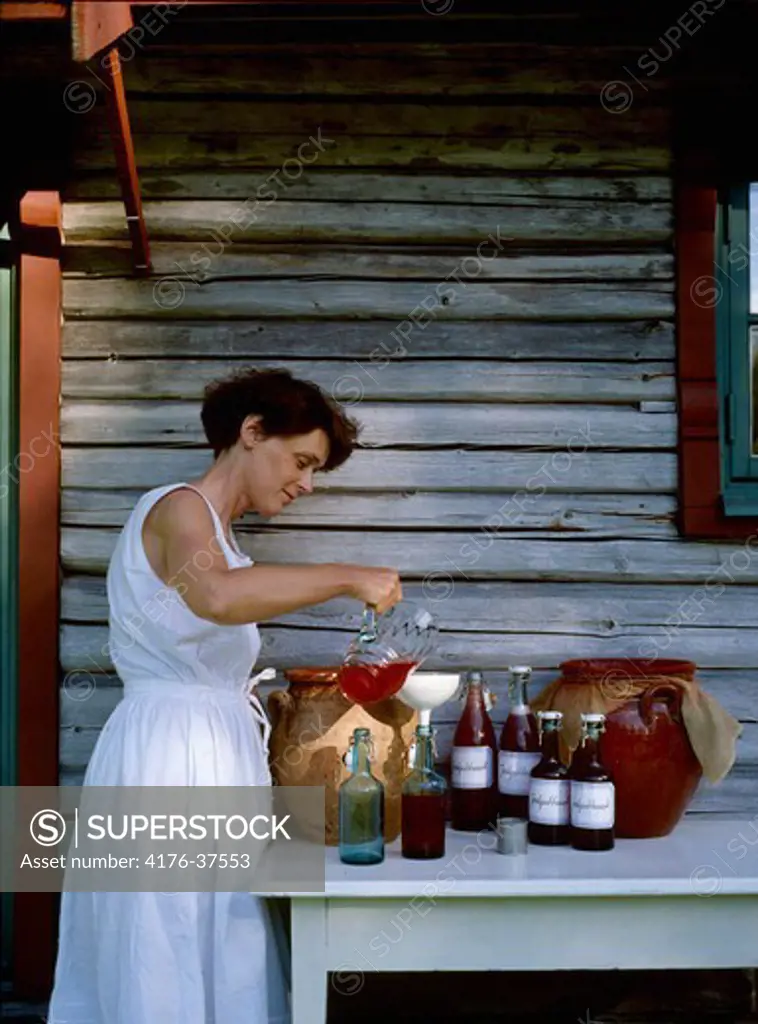 Woman pouring juice into bottle, Sweden